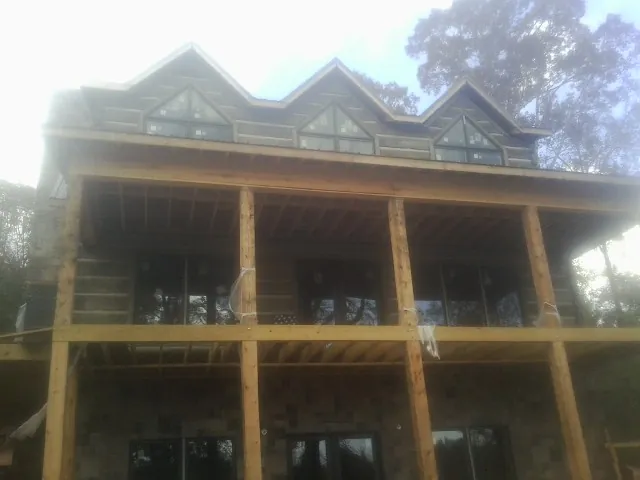 Dormers and porch framing on a large log home under construction — Roof Coating work by our crew in La Crosse